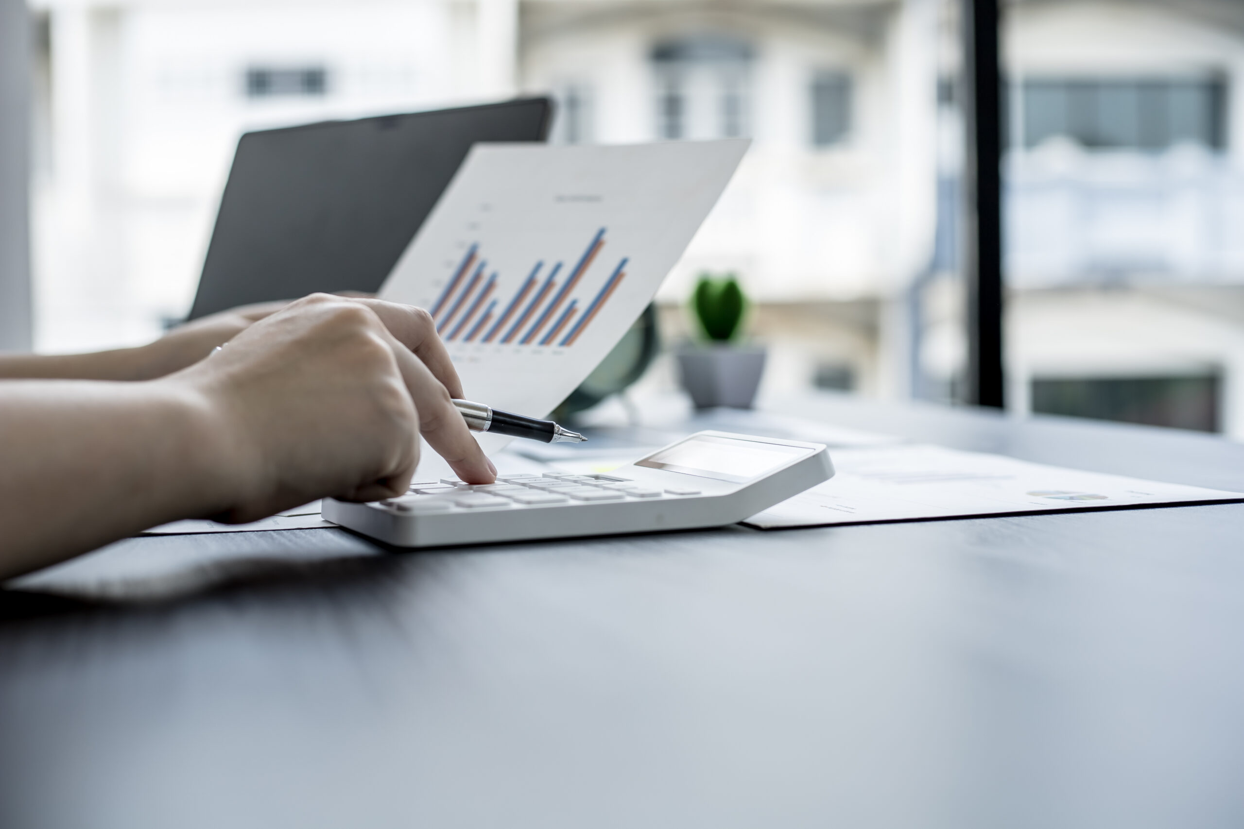 Taschenrechner, auf dem getippt wird und ausgedrucktes Bild von Kostenaufstellung.